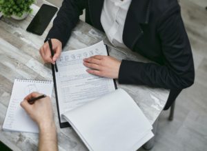 A person is signing papers on top of a table.