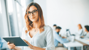 A woman in glasses is holding a tablet