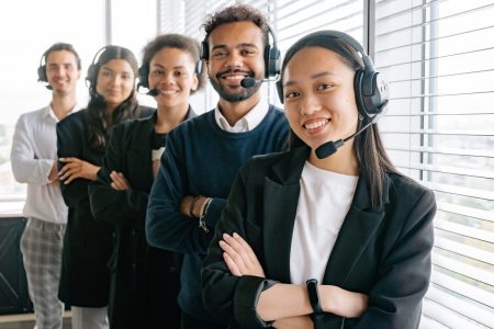 happy-call-center-agents A group of people wearing headphones and smiling.